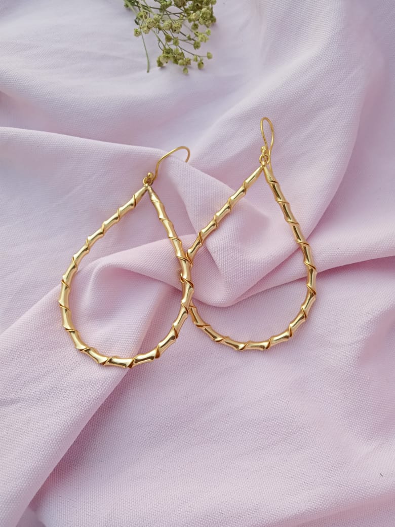 Gold hoop earrings on a pink fabric background